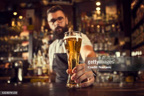 bartender serving beer - bartender stock pictures, royalty-free photos & images