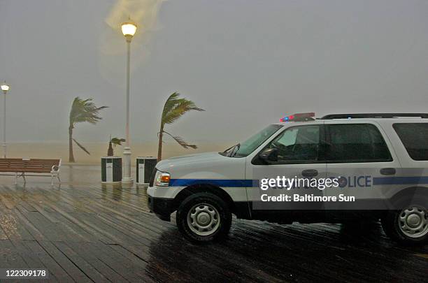 Palm trees bow from storm gusts as a police vehicle patrols the boardwalk as rain and winds preceding the full impact of Hurricane Irene hit Ocean...