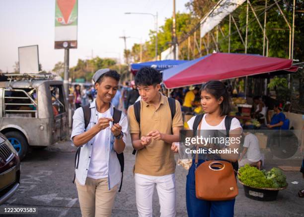 young asian friends eating local food on street - philippines friends stock pictures, royalty-free photos & images