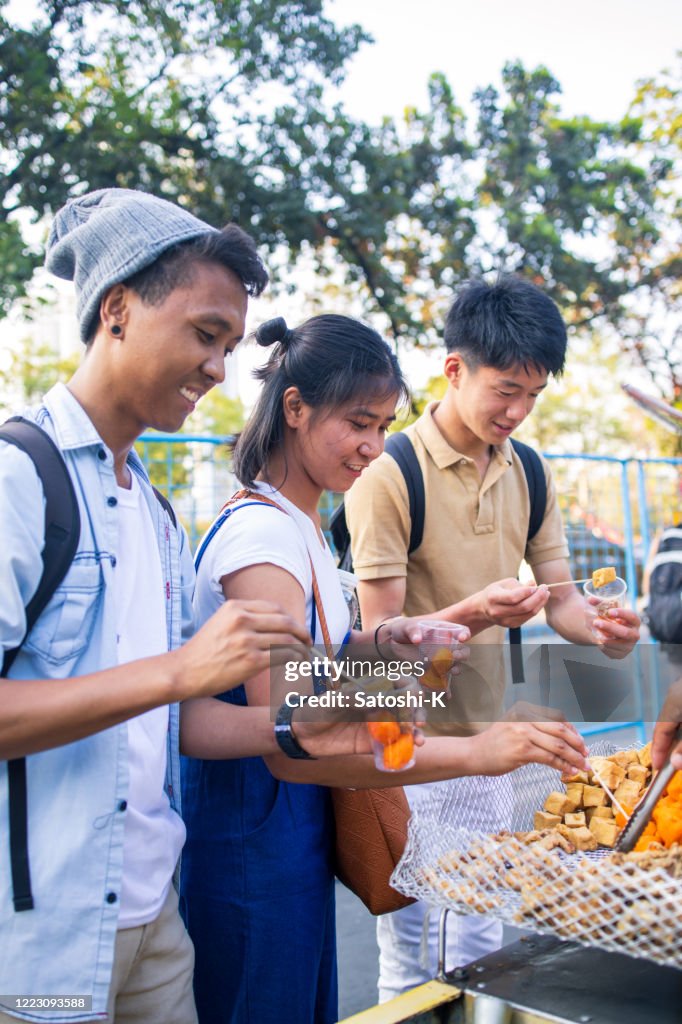 Young Asian friends picking up street food