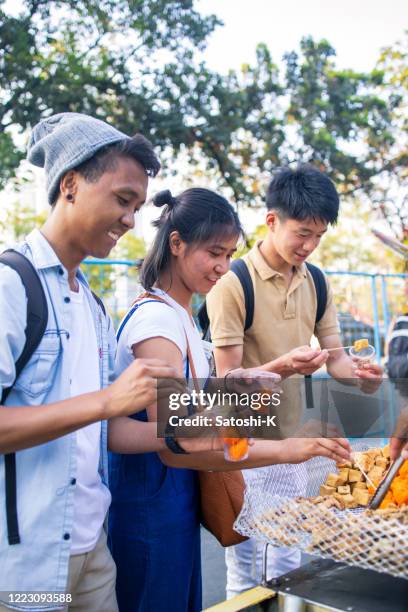 young asian friends picking up street food - daily life in manila stock pictures, royalty-free photos & images