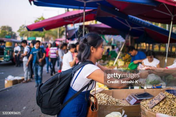 giovane donna asiatica che compra cibo alla bancarella di cibo di strada - filipino foto e immagini stock