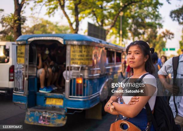 junge asiatische frau wartet auf einen jeepney zu kommen - national capital region philippines stock-fotos und bilder