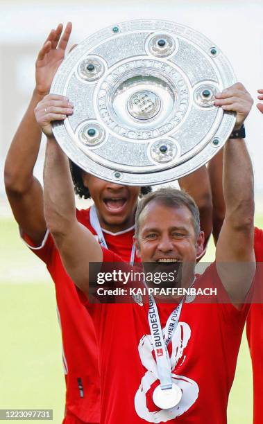 Bayern Munich's German head coach Hans-Dieter Flick lifts the trophy as Bayern Munich players celebrate winning the German Bundesliga after the...