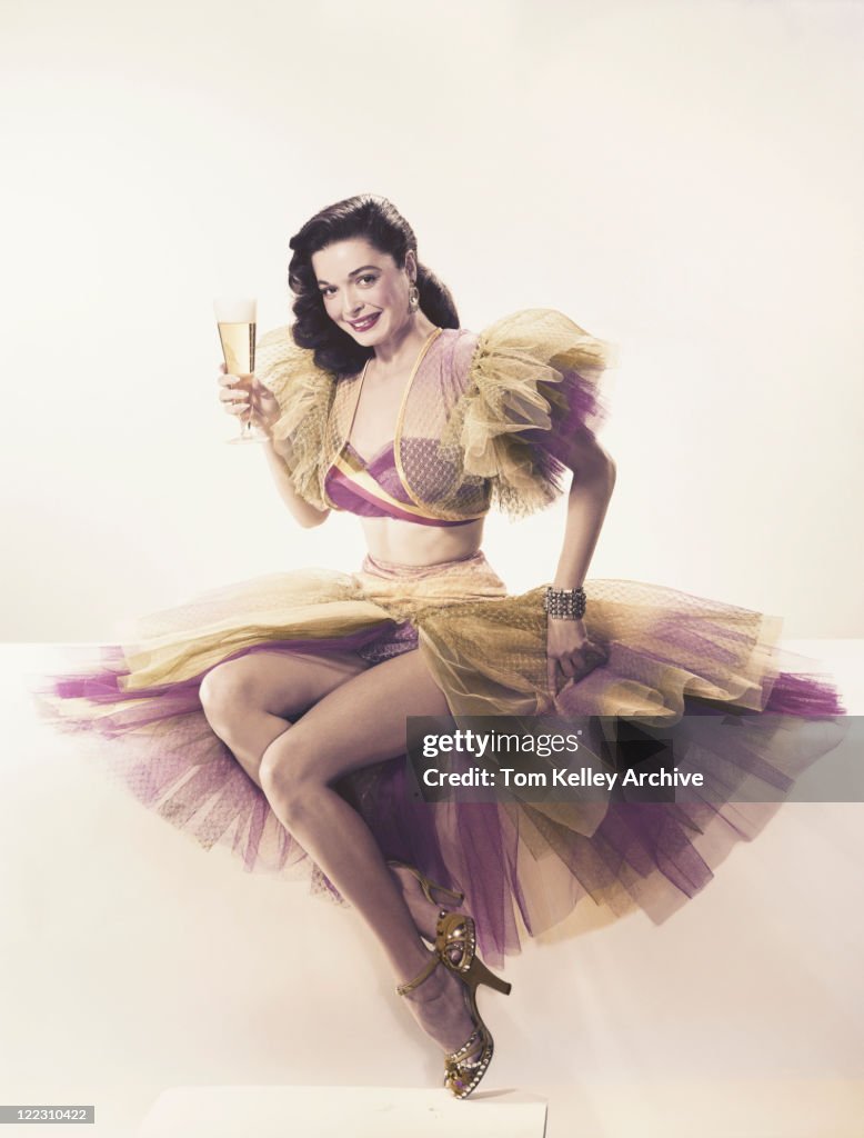 Young woman in ruffled dress holding beer glass, portrait