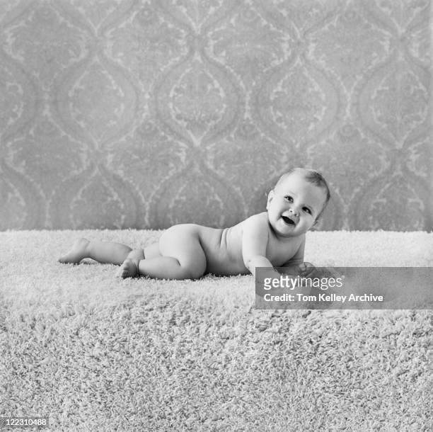 baby boy lying on rug, smiling - 1960s baby stockfoto's en -beelden