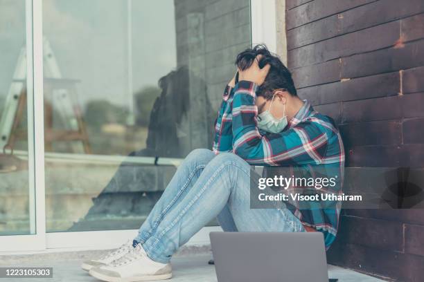 young men wearing protective mask to protect against covid-19 worried about unemployment - alone in a crowd sad stockfoto's en -beelden