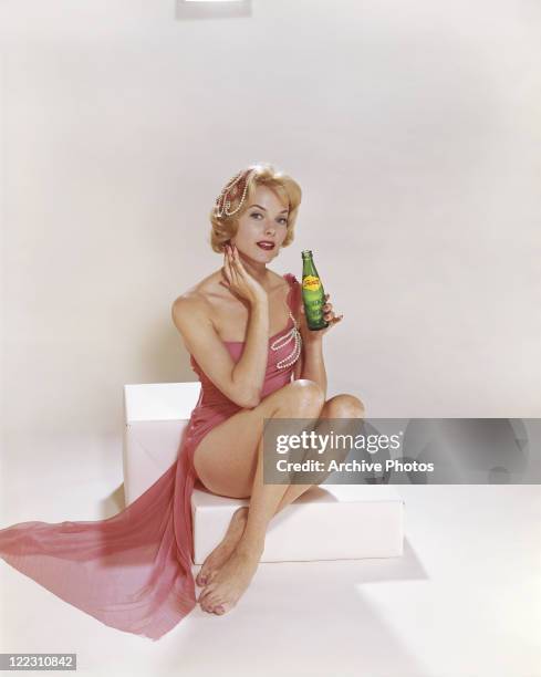 Young woman holding cold drink bottle, portrait