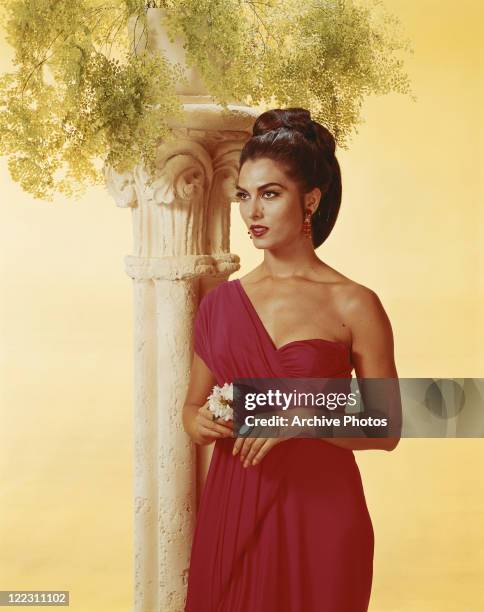 Young woman standing beside pedestal holding flower