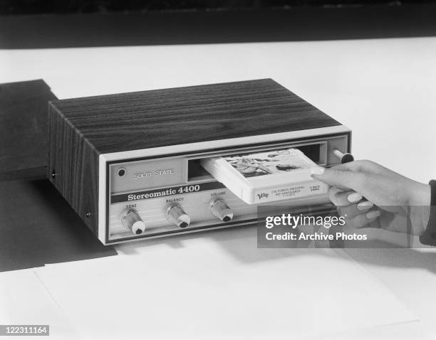 Woman inserting cassette tape in cassette player, close-up