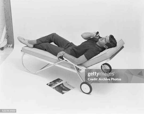 Man lying on sun lounger smoking pipe