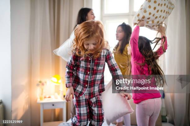 group of small girl friends having pillow fight on bed. - luta de almofada imagens e fotografias de stock