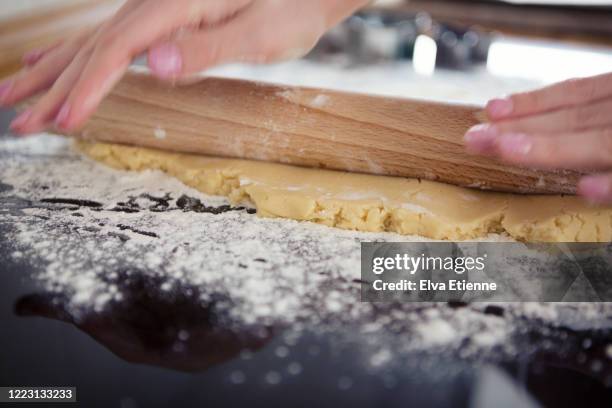 close-up of the hands of a teenager rolling out freshly made dough on a floured surface in a kitchen - all purpose flour stockfoto's en -beelden