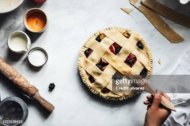 frau bürstet eine typische fruchtgitter kuchen - sweet pie stock-fotos und bilder