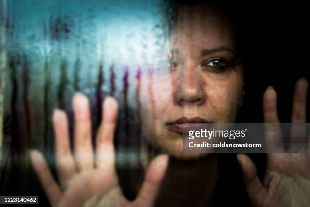 depressed woman looking out of rainy window - violence stock pictures, royalty-free photos & images