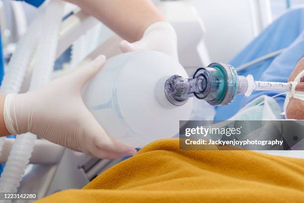 doctor holding oxygen ambu bag over patient given oxygen to patient by intubation tube in icu/emergency room - coronavirus 2019 stock pictures, royalty-free photos & images