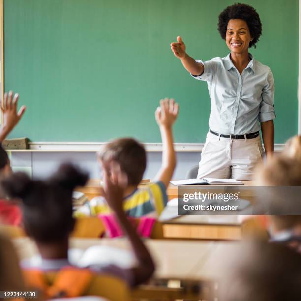 heureux professeur d’école afro-américaine visant à l’écolier pour répondre à sa question. - enseignante photos et images de collection