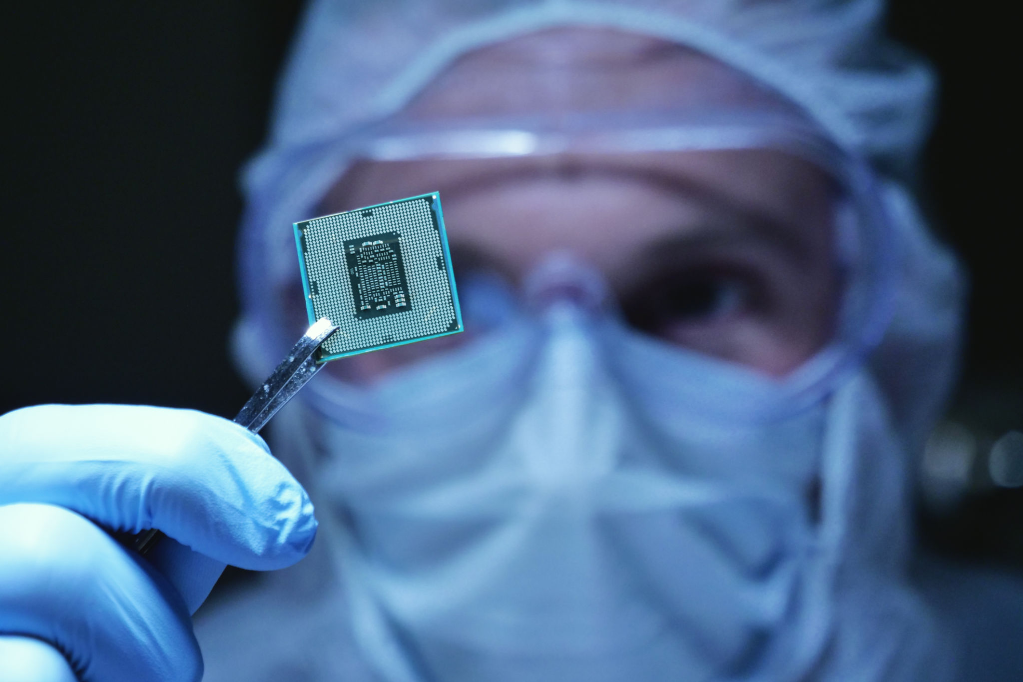 in Ultra Modern Electronic Manufacturing Factory Design Engineer in Sterile Coverall Holds Microchip with symbols in futuristic holography. in Ultra Modern Electronic Manufacturing Factory Design Engineer in Sterile Coverall Holds Microchip with symbols in futuristic holography.