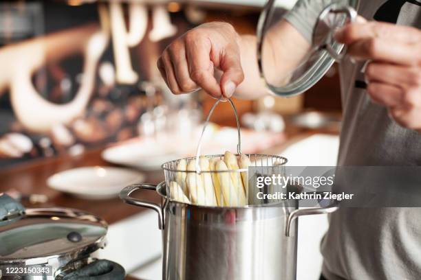 home cooking: man boiling white asparagus, using special pot - asparagus stock-fotos und bilder