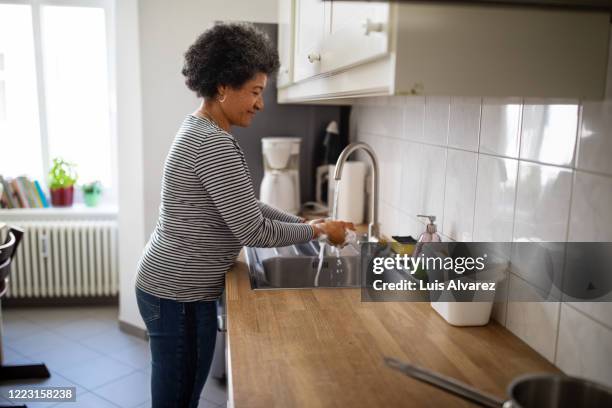 mature woman washing her hands to prevent corona virus infection - washing hands stock pictures, royalty-free photos & images