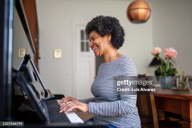 mature woman learning playing piano during home quarantine - photograph 51 play stockfoto's en -beelden