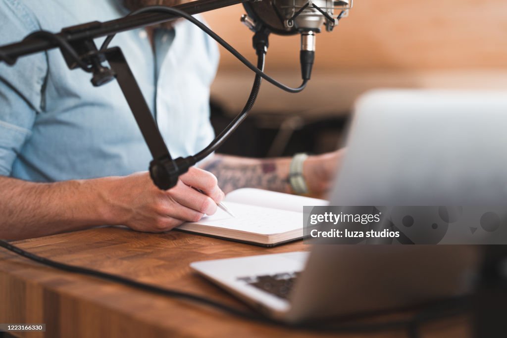 Hombre tomando notas mientras graba un podcast