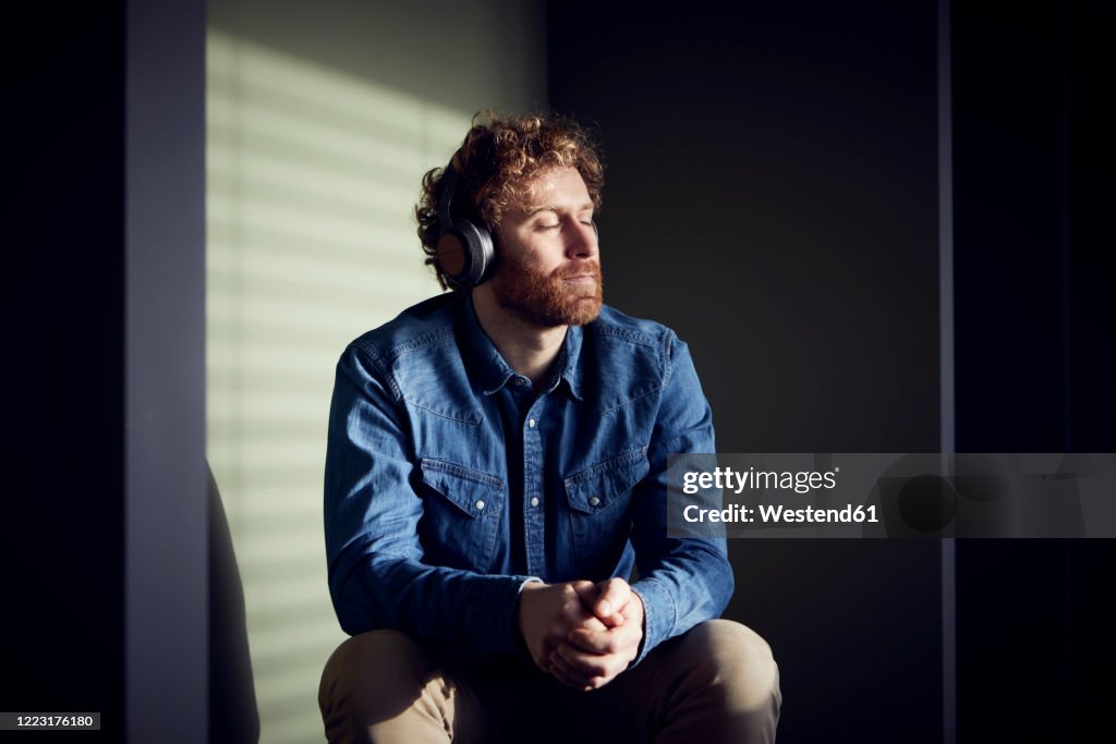 Relaxed casual businessman sitting down listening to music with headphones