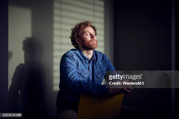 relaxed casual businessman sitting down with closed eyes - tranquility stock-fotos und bilder