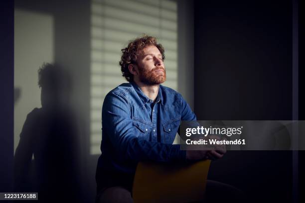 relaxed casual businessman sitting down with closed eyes - blue cup stockfoto's en -beelden