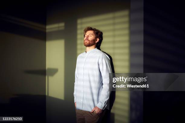 casual businessman with closed eyes leaning against a wall - vida sencilla fotografías e imágenes de stock