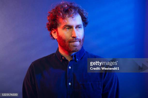 portrait of a man at a blue wall - color image stockfoto's en -beelden