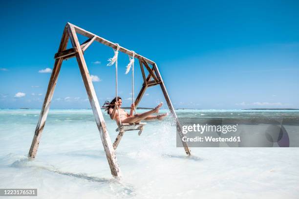 woman swinging on swing in the sea, bahamas, caribbean - peeple of caribbean stock-fotos und bilder