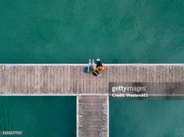 two friends sitting side by side on jetty, valdemurio reservoir, asturias, spain - steg zwei menschen stock-fotos und bilder