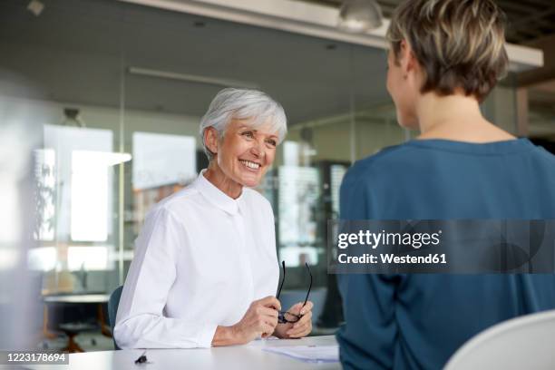 two businesswomen talking at desk in office - white blouse stock pictures, royalty-free photos & images