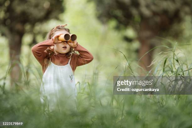 närbild porträtt av liten flicka tittar genom en kikare söker efter en fantasi eller utforskning på våren i parken. - toilet paper tree bildbanksfoton och bilder