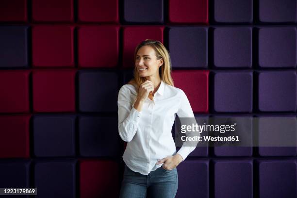 portrait of smiling woman at a purple wall - purple blouse stock pictures, royalty-free photos & images