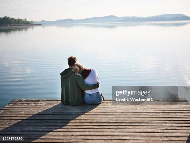 romantic couple sitting on jetty at the lake - bathing jetty stock pictures, royalty-free photos & images