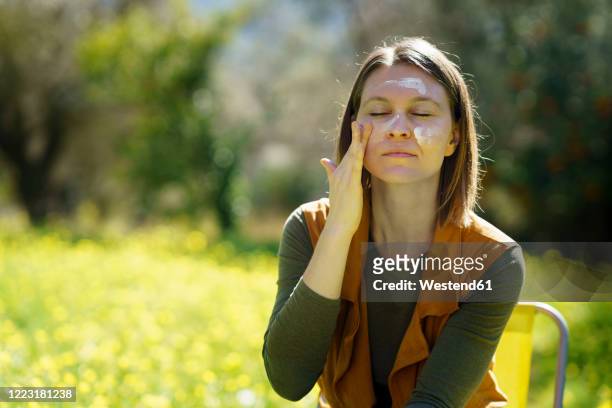 young woman applying sunscreen in the countryside - applying sunblock stock pictures, royalty-free photos & images