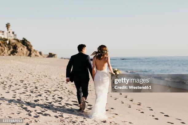 rear view of happy bridal couple running at the beach - wedding photos 個照片及圖片檔