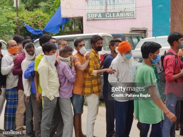 People at a queue wait to buy alcohol during the COVID-19 pandemic on May 6, 2020 in New Delhi, India. The government of Delhi imposed a special tax...
