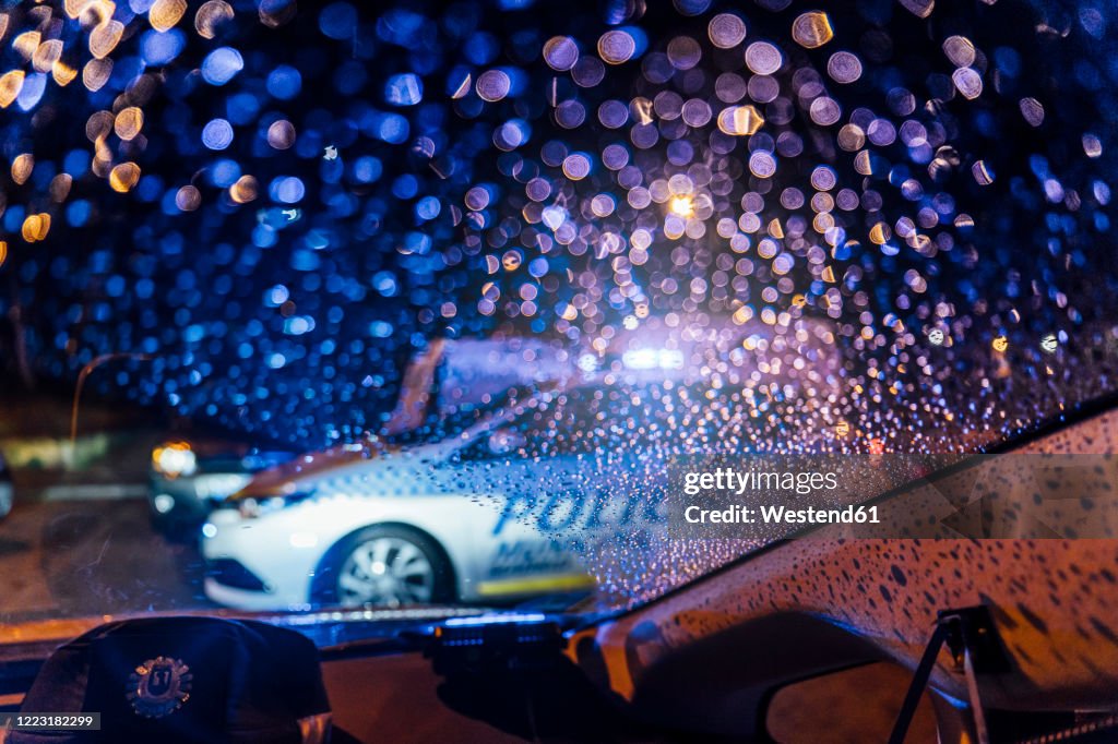 Spain, Madrid, Interior of car parked in front of patrolling police car at night