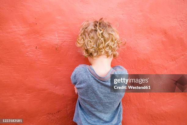 back view of  little boy standing in front of red wall - 6 7 jahre stock-fotos und bilder