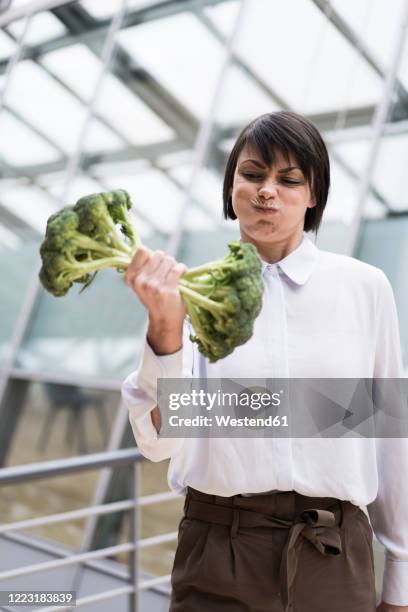 businesswoman doing weight training with broccoli - funny vegetable stock-fotos und bilder