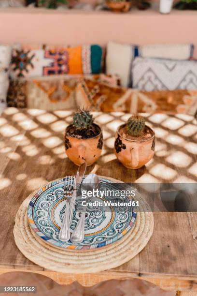 morocco, table with two potted cacti and cutlery lying on ornate plate - morocco interior ストックフォトと画像