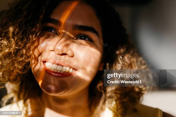 portrait of happy young woman in sunlight - visages stock pictures, royalty-free photos & images