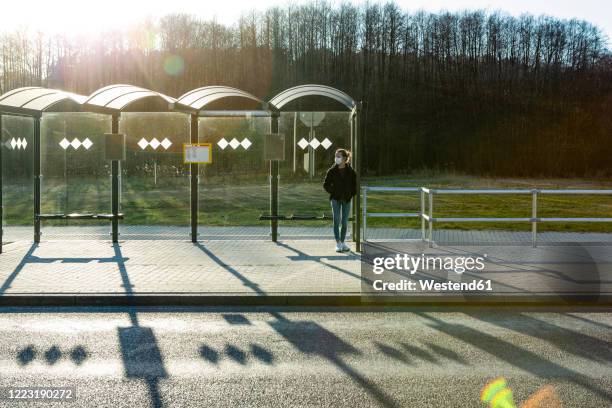 portrait of a girl with mask waiting at bus stop - bus shelter stock pictures, royalty-free photos & images