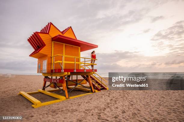 woman in red swimsuit on lifeguard hut on miami beach, miami, florida, usa - miami people stock pictures, royalty-free photos & images