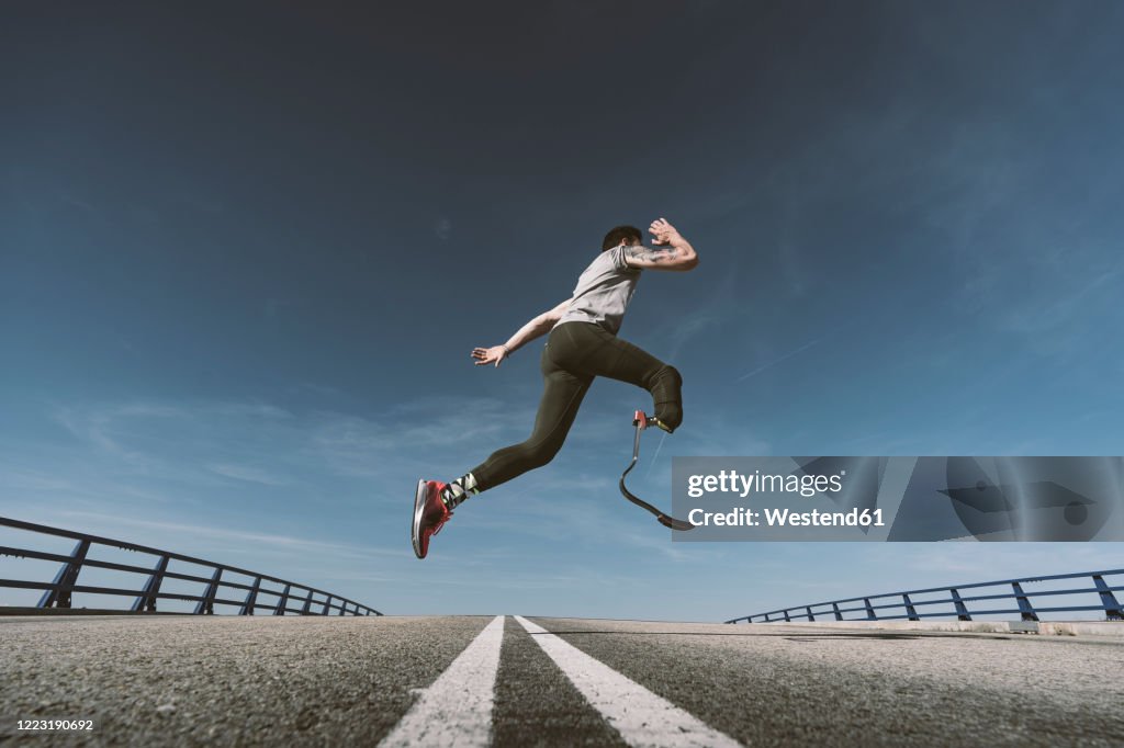 Disabled athlete with leg prosthesis exercising on a road