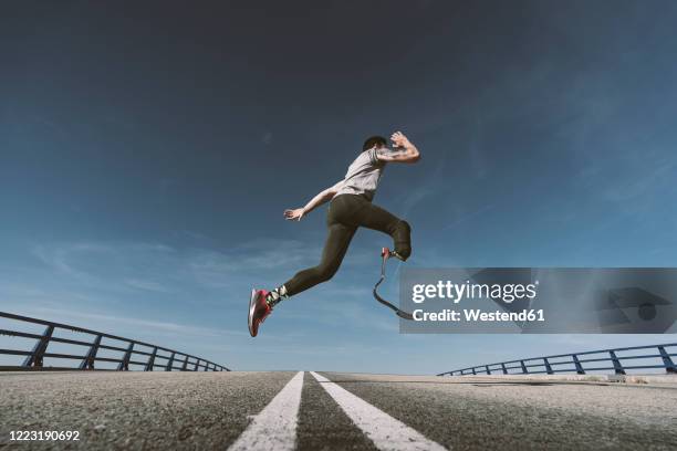 disabled athlete with leg prosthesis exercising on a road - artificial limb stockfoto's en -beelden