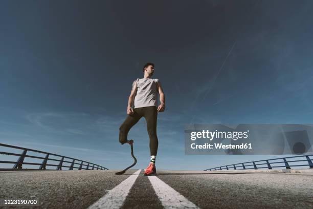 disabled athlete with leg prosthesis standing on a road - disabled athlete foto e immagini stock